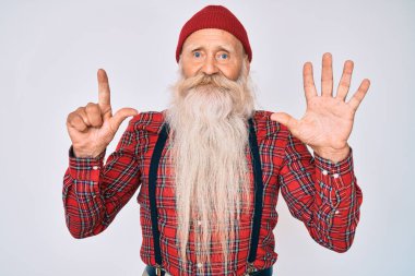 Gri saçlı, uzun sakallı, hippi görünümlü yaşlı bir adam. Yün şapkalı ve yedi numaralı parmaklarıyla işaret ediyor. Kendinden emin ve mutlu bir şekilde gülümsüyor.. 