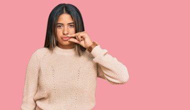 Kışın yün kazak giyen genç Latin kız ağzı ve parmaklarıyla fermuar gibi kapanan dudaklar. gizli ve sessiz, tabu konuşması 