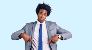 Yakışıklı Afro saçlı, iş ceketi giyen üzgün ve üzgün görünen, parmaklarıyla yön gösteren, mutsuz ve depresif bir Amerikalı.. 