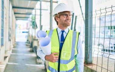 Bir bina projesinin dışında dikilirken yansıtıcı yelek giyen bir mimar.
