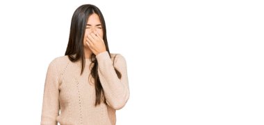 Genç esmer kadın sıradan bir kazak giyiyor. Kokuşmuş ve iğrenç bir koku alıyor. Dayanılmaz bir koku. Kötü kokuyor. 