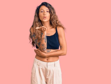 Gündelik giysiler giymiş genç İspanyol bir kadın kameraya bakıp havada el sallayarak öpüşüyor ve çok güzel ve seksi oluyor. aşk ifadesi. 