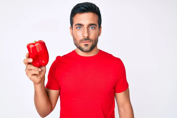 Young Hispanic Man Holding Red Pepper Thinking Attitude Sober Expression — Stock Photo, Image