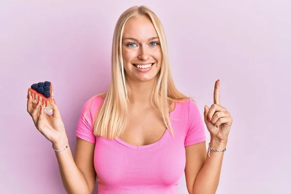 Jovem Loira Segurando Fatias Cheesecake Sorrindo Com Uma Ideia Pergunta — Fotografia de Stock