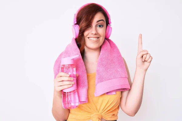 Joven Hermosa Mujer Con Toalla Auriculares Sosteniendo Botella Agua Sonriendo —  Fotos de Stock