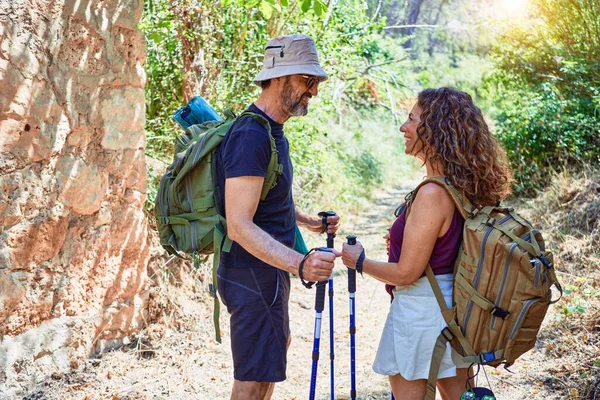 美丽的一对徒步旅行者背着背包开心地笑着 在森林里用手杖徒步旅行时 面带微笑地站在那里 — 图库照片