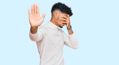 Gündelik kazak giyen genç Arap adam elleriyle gözlerini kapatıyor ve üzgün ve korku ifadeleriyle jest yapıyor. utangaç ve olumsuz kavram. 