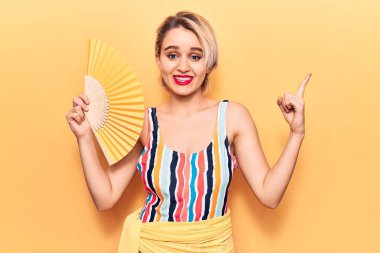 Mayo giyen genç, sarışın bir kadın. El ele tutuşup gülümsüyor. 