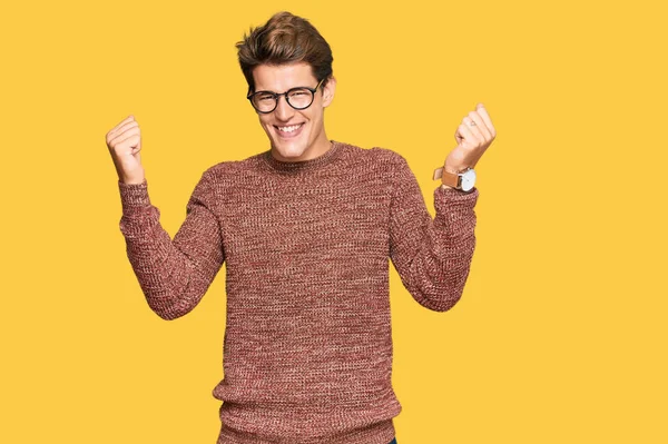 Yakışıklı beyaz adam, sıradan süveter ve gözlük takıyor gururla bağırıyor, zaferi kutluyor ve başarıyı kollarını kaldırarak kutluyor. 