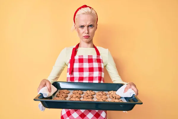 Ung Blond Kvinna Bär Bagare Uniform Håller Hemmagjorda Kakor Skeptisk — Stockfoto