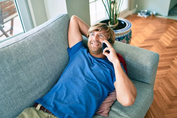 中世ハンサムなCucasian男リラックスしています上のソファ上で電話で話す自宅 — ストック写真
