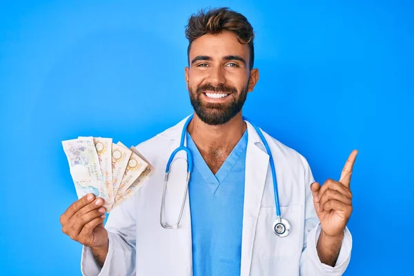Jovem Hispânico Homem Vestindo Médico Uniforme Segurando Libras Notas Sorrindo — Fotografia de Stock