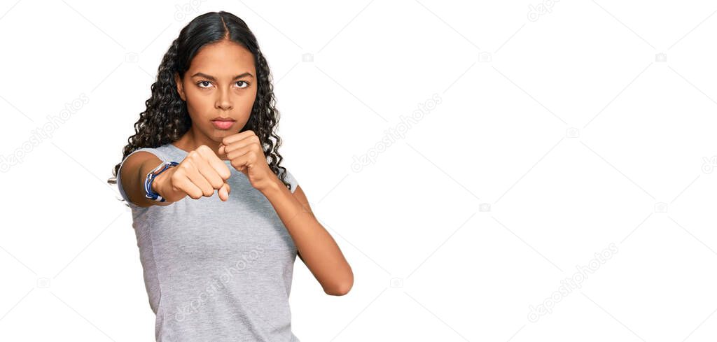 Young african american girl wearing casual clothes punching fist to fight, aggressive and angry attack, threat and violence 