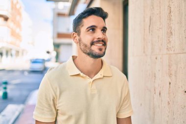 Genç İspanyol adam gülümseyerek şehirde mutlu bir şekilde yürüyor..