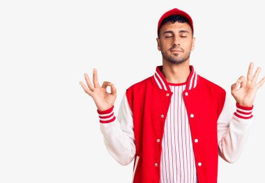 Beyzbol üniforması giyen genç İspanyol adam rahatla ve gözleri kapalı gülümse parmaklarıyla meditasyon hareketi yapıyor. yoga konsepti. 