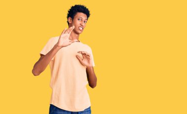 Genç Afro-Amerikalı adam günlük giysiler giyiyordu. İğrenç bir ifade takınıyordu. Tiksinti tepkisi yüzünden tiksinmiş ve korkuyordu. Eller havada. 