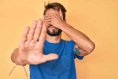 Yakışıklı, sakallı, sıradan kıyafetler giyen, elleriyle gözlerini kapatan, üzgün ve korku ifadeli hareketler yapan beyaz adam. utangaç ve olumsuz kavram. 