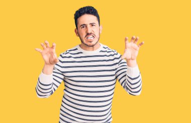 Gündelik kıyafetler giyen genç İspanyol adam komik gülüyor kedi gibi pençe hareketi yapıyor, agresif ve seksi bir ifade. 