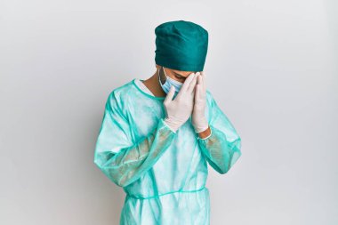 Cerrah üniforması giyen genç yakışıklı bir adam ve ağlarken yüzünü ellerle kapatan üzgün bir tıbbi maske takıyor. depresyon kavramı. 