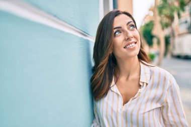 Genç İspanyol kadın gülümsüyor mutlu bir şekilde şehrin duvarına yaslanıyor..