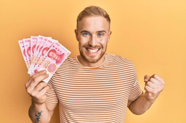 Kafkasyalı genç adam 100 yuan Çin banknotları tutuyor gururla bağırıyor, zaferi kutluyor ve başarıyı kollarını kaldırarak kutluyor. 