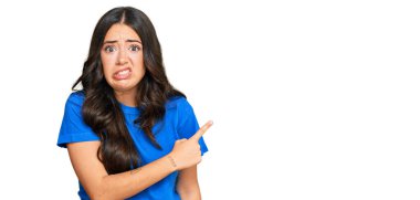 Güzel esmer, gündelik kıyafetler giyen genç bir kadın endişeli ve gergin bir şekilde işaret ediyor. 