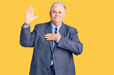 Üstün gri saçlı, iş ceketi giyen, el pençe divan duran, sadakat yemini eden bir adam. 