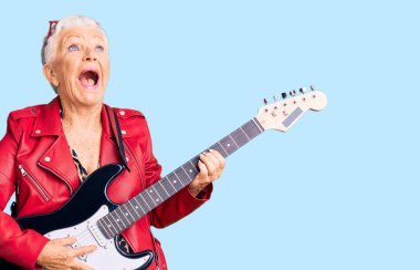 Son sınıf güzeli, mavi gözlü, gri saçlı, modern görünümlü, kızgın ve kızgın bir şekilde gitar çalan öfkeli ve öfkeli, öfkeyle bağıran bir kadın. öfke ve agresif konsept. 