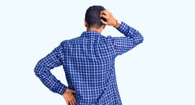 Genç Afrikalı Amerikalı bir adam günlük kıyafetlerini ters giyip elleri kafasında şüpheyi düşünüyor. 