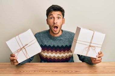 Elinde hediyeler tutan genç yakışıklı adam şaşkınlık ve şaşkınlık içinde bir ifade, korku ve heyecanlı bir yüz.. 