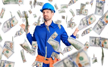 Genç, yakışıklı bir adam işçi üniforması giyiyor ve yüksek sesli müzik sesi için kulaklarını parmaklarıyla kapatıyor. sağır kavramı.