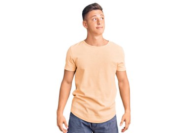 Gündelik kıyafetler giyen genç yakışıklı adam gülümseyerek yan tarafa bakıyor ve düşünüyor.. 