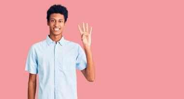 Genç Afro-Amerikalı günlük kıyafetler giymiş dört numarayı gösterip işaret ederken kendinden emin ve mutlu bir şekilde gülümsüyor.. 