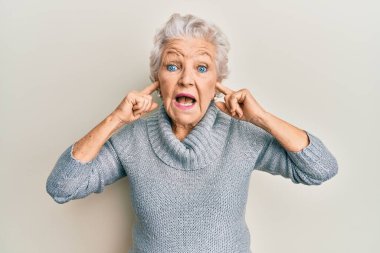 Yaşlı, gri saçlı, kulaklarını parmaklarıyla kapatan bir kadın. Çılgınlığı kutluyor ve başarı için hayrete düşüyor. Gözleri açık, heyecanlı çığlıklar atıyor.. 