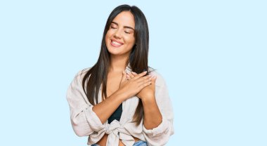 Gündelik kıyafetler giyen, göğsünde elleri kapalı, yüzünde minnet dolu bir jest olan genç, güzel İspanyol bir kız. sağlık kavramı. 