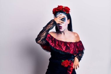 Meksika makyajı yapan genç bir kadın. Şoka girmiş, yüzünü ve gözlerini kapamış, utanmış bir ifadeyle parmaklarının arasından bakıyor.. 