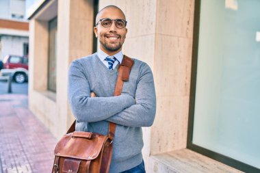 Genç Afrikalı Amerikalı iş adamı gülümseyerek şehirde mutlu bir şekilde yürüyor..
