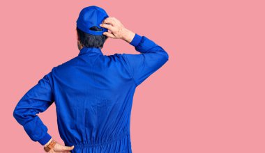 Tamirci üniforması giyen orta yaşlı yakışıklı adam, elleri kafasında şüpheyi geriye doğru düşünüyor. 