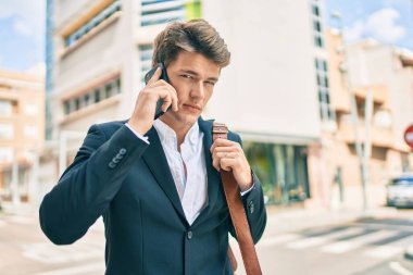 Kafkasyalı genç iş adamı ciddi bir ifadeyle şehirdeki akıllı telefondan konuşuyor..