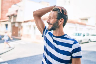 Sakallı yakışıklı beyaz adam, dışarıda mutlu bir şekilde gülümsüyor.