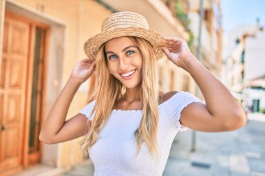 Genç sarışın turist kız gülümseyerek şehirde mutlu bir şekilde yürüyor..