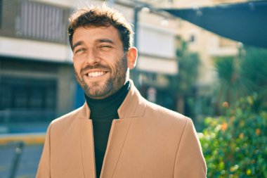 Zarif ceket giyen yakışıklı iş adamı dışarıda mutlu bir şekilde gülümsüyor.