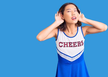 Ponpon kız üniforması giyen genç, güzel Çinli kız iki elini de kulak hareketlerinde duymaya çalışıyor, dedikoduya meraklı. İşitme sorunu, sağır 