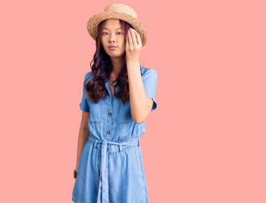 Genç, güzel Çinli kız yaz şapkası takıyor. İtalyan jestleri yapıyor. Elleri ve parmakları ile kendinden emin ifade ediyor. 