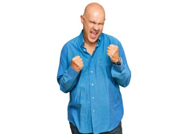 Orta yaşlı kel bir adam kolları havada ve gözleri kapalı bir şekilde başarıyı kutluyor ve şaşırıyor. Kazanan konsept. 