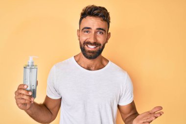 Genç İspanyol adam el dezenfektanı jeli kullanıyor başarıyı mutlu bir gülümsemeyle kutluyor ve kazanan el kaldırarak ifade ediyor. 