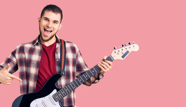 Jovem Homem Bonito Tocando Guitarra Elétrica Sorrindo Feliz Apontando Com — Fotografia de Stock