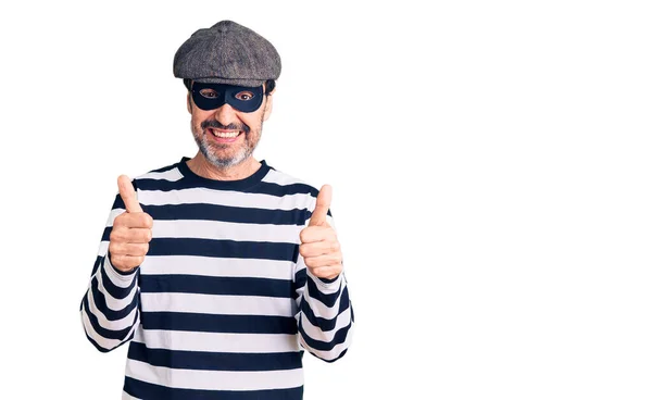 中世のハンサムな男は 手で積極的なジェスチャーを行う泥棒マスクの成功のサインを着て 親指を笑顔と幸せ 陽気な表情と勝者のジェスチャー — ストック写真