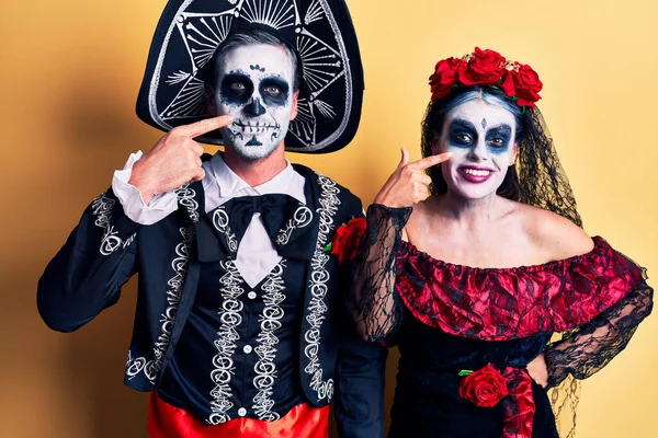 若いカップルの顔と鼻に手の指で黄色のポインティング上に死んだ衣装のメキシコの日を着て 陽気な笑顔 美の概念 — ストック写真