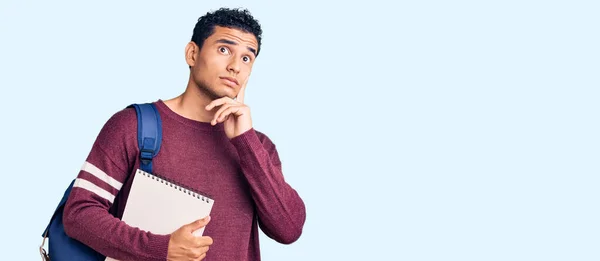 Joven Joven Guapo Hispano Usando Mochila Estudiante Cuaderno Cara Seria —  Fotos de Stock